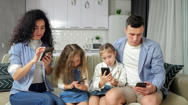 Die Familie sitzt, schaut sich Smartphones an und erkundet das Internet