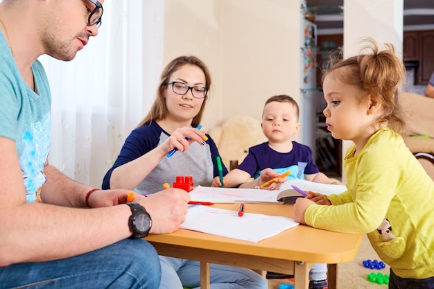 Die Familie zeichnet Bleistifte an einem Tisch im Zimmer