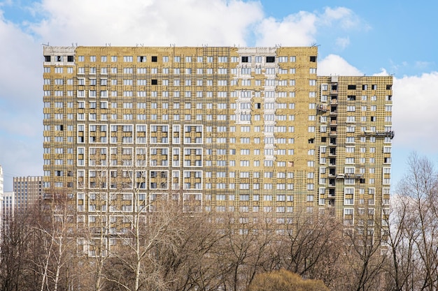 Die Fassade eines im Bau befindlichen mehrstöckigen Gebäudes gegen den blauen Himmel