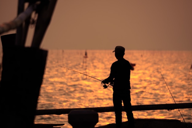 Die Fischerschattenbild mit Sonnenuntergangshimmel