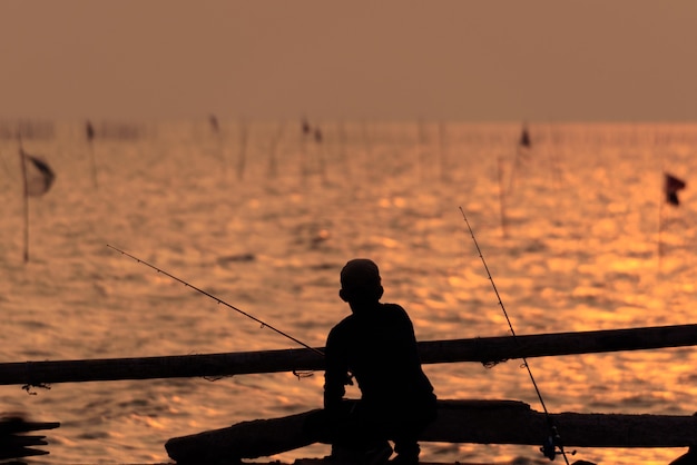 Die Fischerschattenbild mit Sonnenuntergangshimmel