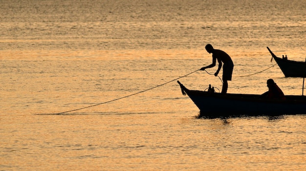 Foto die fischersilhouette legt morgens sein fangnetz nieder