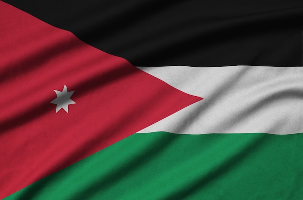 Die Flagge Jordaniens ist auf einem Sportstoff mit vielen Falten abgebildet.