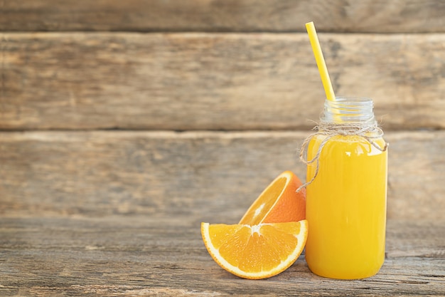 Die Flasche Orangensaft und Orangenscheiben auf dem Holztisch wooden