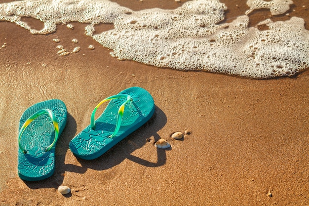 Die Flipflops der Frauen stehen auf dem Strand auf dem Sand, Ferienkonzept