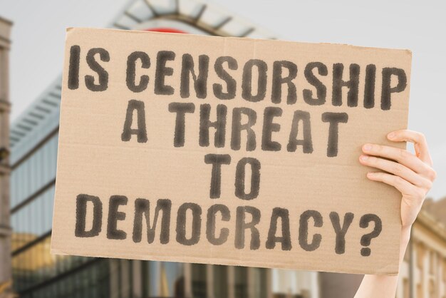 Die Frage „Ist Zensur eine Bedrohung für die Demokratie“ steht auf einem Banner in Männerhänden mit verschwommenem Hintergrund Sicherheitszensur Zensurbehörde Regierung Internet-Netzwerk Presse Soziales