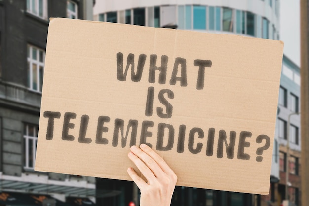 Die Frage, was Telemedizin ist, steht auf einem Banner in Männerhänden mit verschwommenem Hintergrund