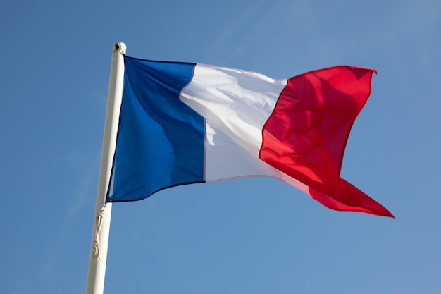 Die französische Nationalflagge schwebt vor blauem Himmel