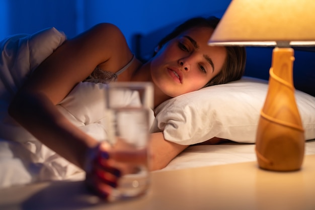 Die Frau auf dem Bett mit einer Alkoholspritze