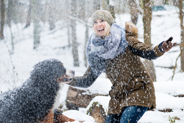 Die Frau, die ihren Hund im Winter geht, und beide erforschen den Schnee zu