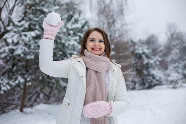 Die Frau hält den Schneeball in ihren Händen. Sie trägt warme Kleidung. Konzentrieren Sie sich auf ihre Hände und ihren Schneeball