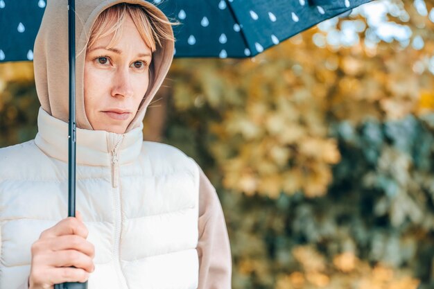 Die Frau ist im Herbstpark mit einem Regenschirm Herbstatmosphäre