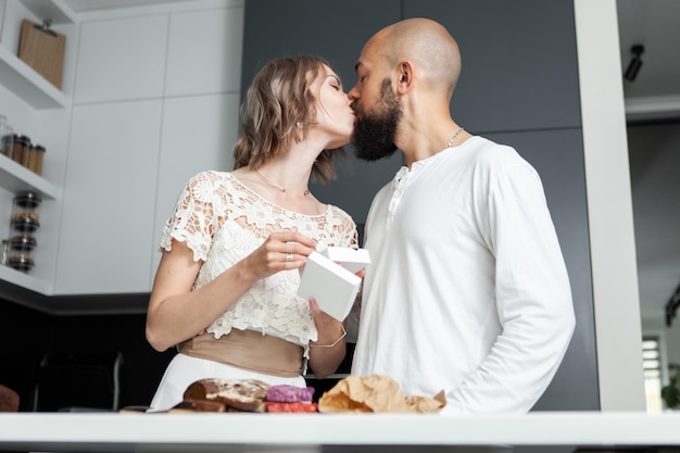 Die Frau küsst ihren Mann und dankt ihm für das Geschenk, das er ihr in der Küche gemacht hat. Liebesromantisches Konzept