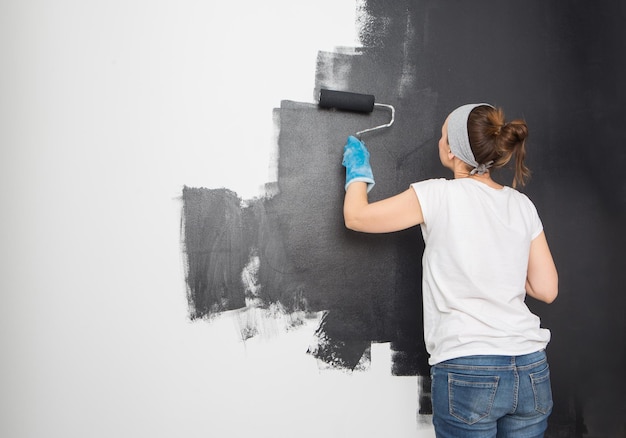 Die Frau malt die Wand mit schwarzer Farbe Renovierung der Wohnküche Reparatur von Wohnungen