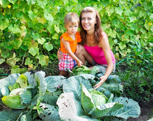 Foto die frau mit dem kind neben dem kohl im garten