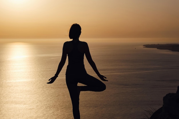 Die Frau mit Yogalage auf dem Berg bei Sonnenuntergang.