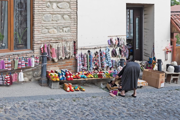 Die Frau neben einem Straßenladen, der Strickwaren verkauft