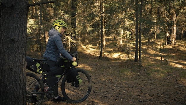 Die Frau reist auf gemischtem Gelände Radtouren mit dem Fahrrad Bikepacking im Freien Die Reise des Reisenden mit Fahrradtaschen Stilvolle Bikepacking-Bike-Sportbekleidung in grün-schwarzen Farben Magischer Waldpark