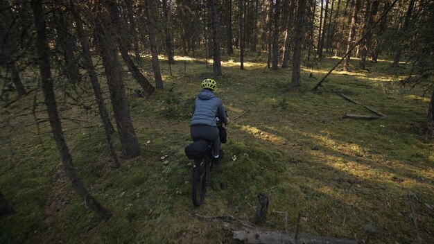 Die Frau reist auf gemischtem Gelände Radtouren mit dem Fahrrad Bikepacking im Freien Die Reise des Reisenden mit Fahrradtaschen Stilvolle Bikepacking-Bike-Sportbekleidung in grün-schwarzen Farben Magischer Waldpark