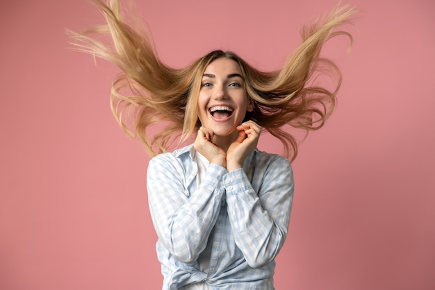 Die freche Blondine wirft ihre Haare, sie fliegen in die Luft