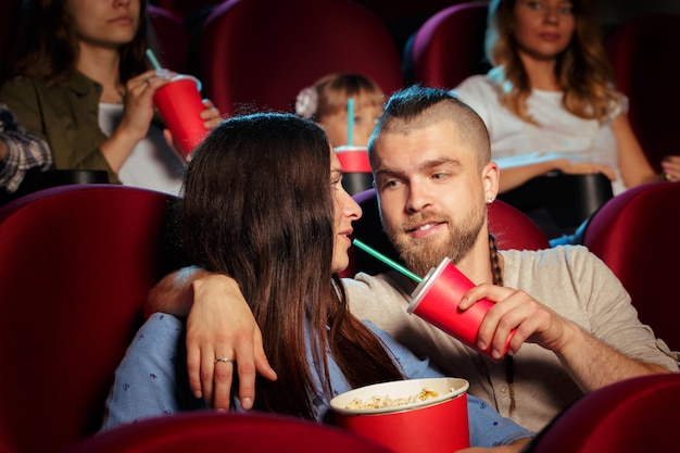 Die Freunde, die im Kino sitzen, passen Film auf, Popcorn und Trinkwasser essend.