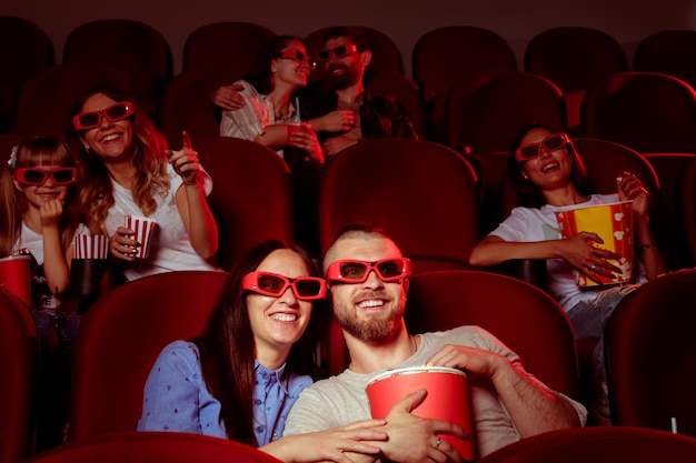 Die Freunde, die im Kino sitzen, passen Film auf, Popcorn und Trinkwasser essend.