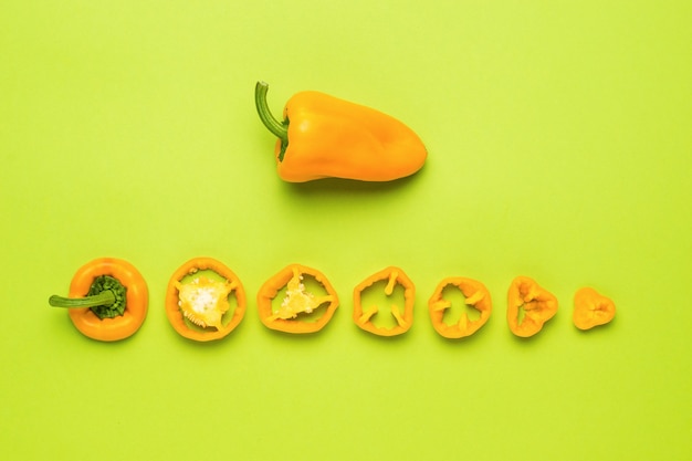 Die Frucht einer ganzen Paprika und in Stücke geschnitten auf grünem Hintergrund. Vegetarisches Essen.