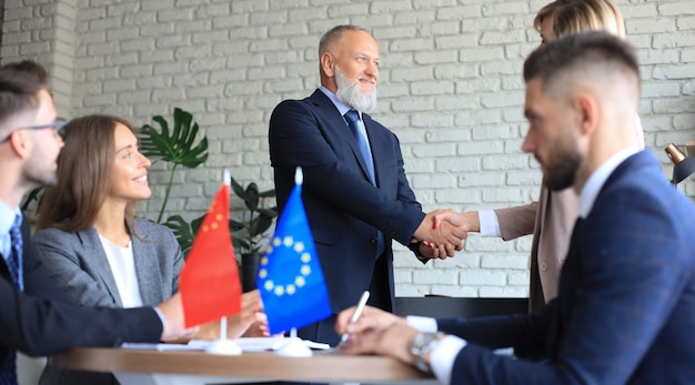 Foto die führer der europäischen union und chinas geben sich bei einem deal die hand.