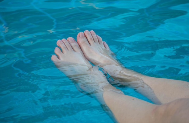 Die Füße der Frau kühlen im klaren blauen Wasser ab