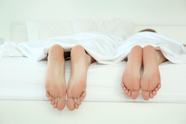 Die Füße des Paares in der Bettnahaufnahme