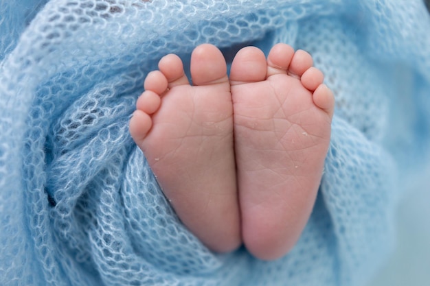 Die Füße eines Babys sind mit einer blauen Decke bedeckt.