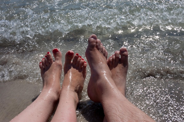 Die Füße eines Paares sind am Strand vor dem Ozean