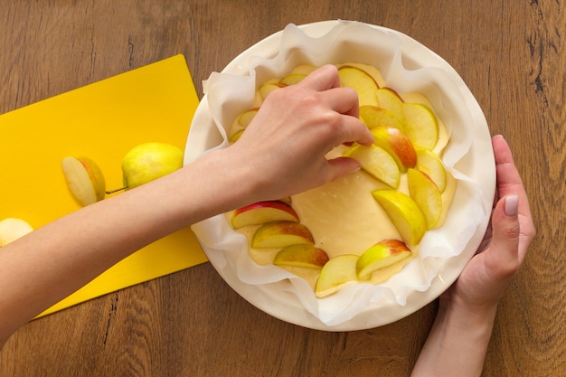 Die Gastgeberin zu Hause bereitet Apfel Charlotte in der Küche zu. legt Zutaten auf Apfelkuchen