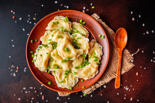 Die gekochten Mehlklöße mit einer Füllung mit Öl und Frühlingszwiebeln auf einem dunklen Tisch. Es kann als Hintergrund verwendet werden