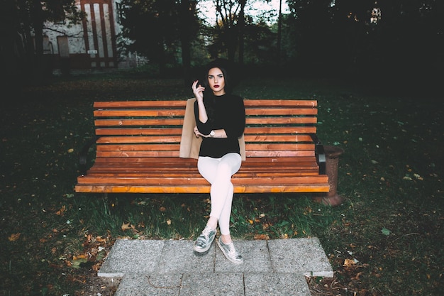 Die gesamte Länge der jungen Frau, die im Park sitzt