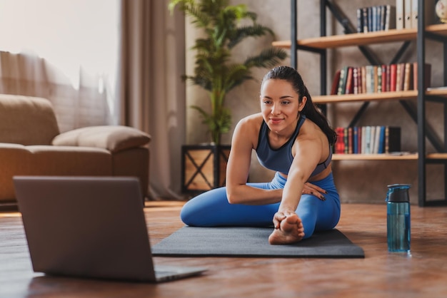 Die gesamte Länge einer jungen Dame, die zu Hause Yoga übt, während sie stürzt