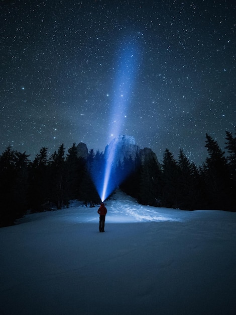 Foto die gesamte länge einer person, die ein blitzlicht hält, während sie auf einem schneebedeckten feld steht