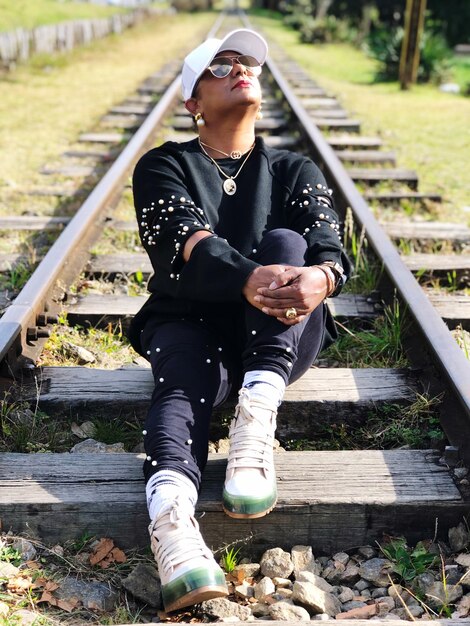 Foto die gesamte länge eines jungen mannes sitzt auf dem schienenbahnstreifen