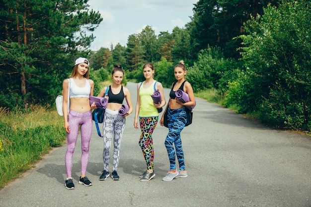 Die Gesellschaft junger attraktiver Freundinnen mit Sportgeräten, die im Park trainieren.