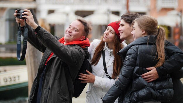 Die Gesellschaft von vier Freunden wird fotografiert und macht ein Selfie an der Uferpromenade von Venedig