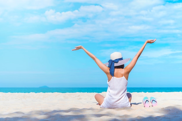 Die Glückfrau, die auf Strand aufhebt, heben Hände bis zum blauen Himmel an