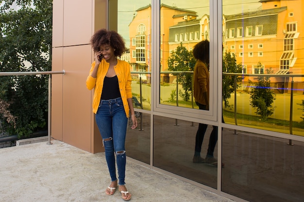 Die glückliche Afroamerikanerin auf der Straße, die am Telefon spricht