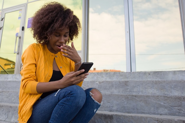 Die glückliche Afroamerikanerin auf der Straße, die am Telefon spricht