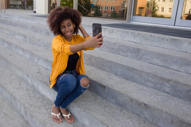 Die glückliche Afroamerikanerin auf der Straße, die am Telefon spricht