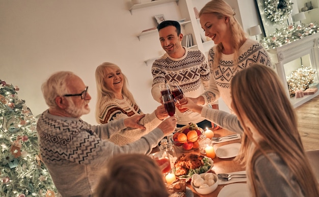 Die glückliche Familie klirrt über dem Weihnachtstisch