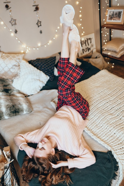 Foto die glückliche frau befindet sich in dem hellen, gemütlichen schlafzimmer, das bis weihnachten wunderschön dekoriert ist