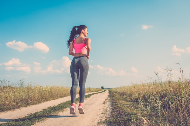 Die glückliche Sportlerin, die im Feldweg läuft