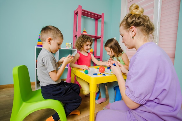 Die glücklichen Kinder mit Erziehern formen aus Plastilin