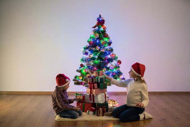 Die glücklichen Kinder spielen neben dem Weihnachtsbaum