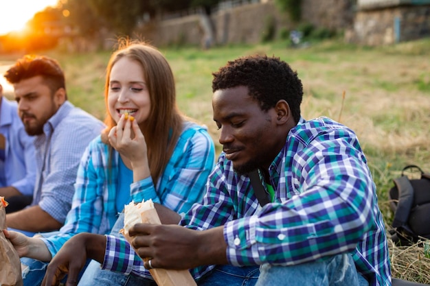 Die glücklichen multiethnischen Studenten genießen ein Fastfood